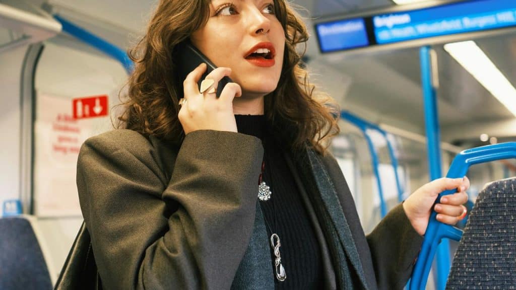 A woman talking on her phone while standing on a train.