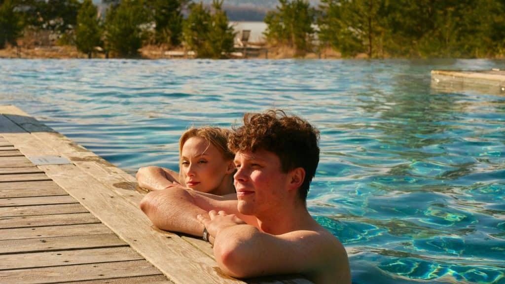 A couple relaxing together in an outdoor swimming pool by the edge.