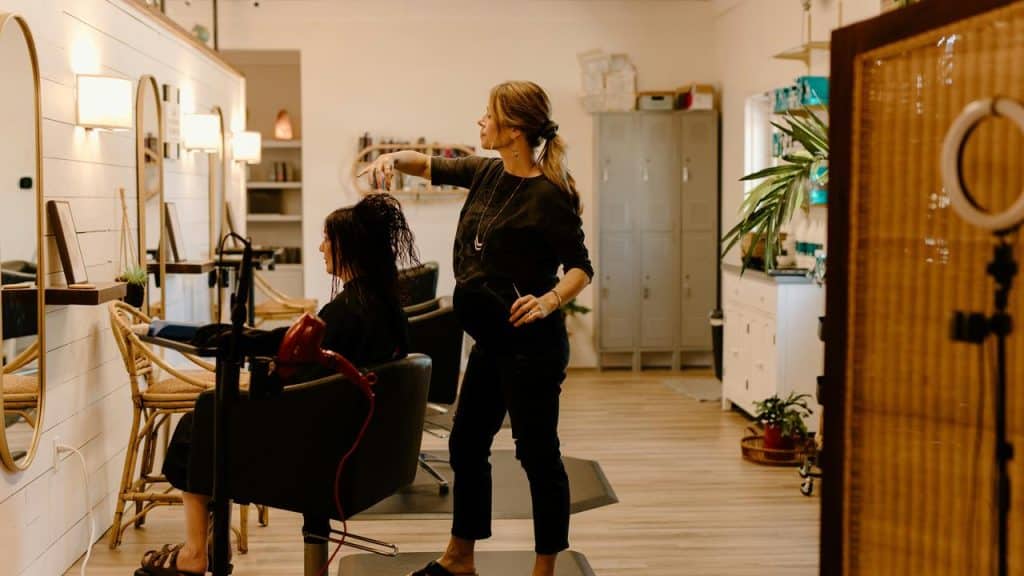 A hairstylist cutting a client’s hair inside a modern salon.
