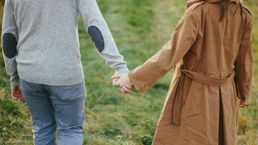 A couple holding hands while walking outdoors.