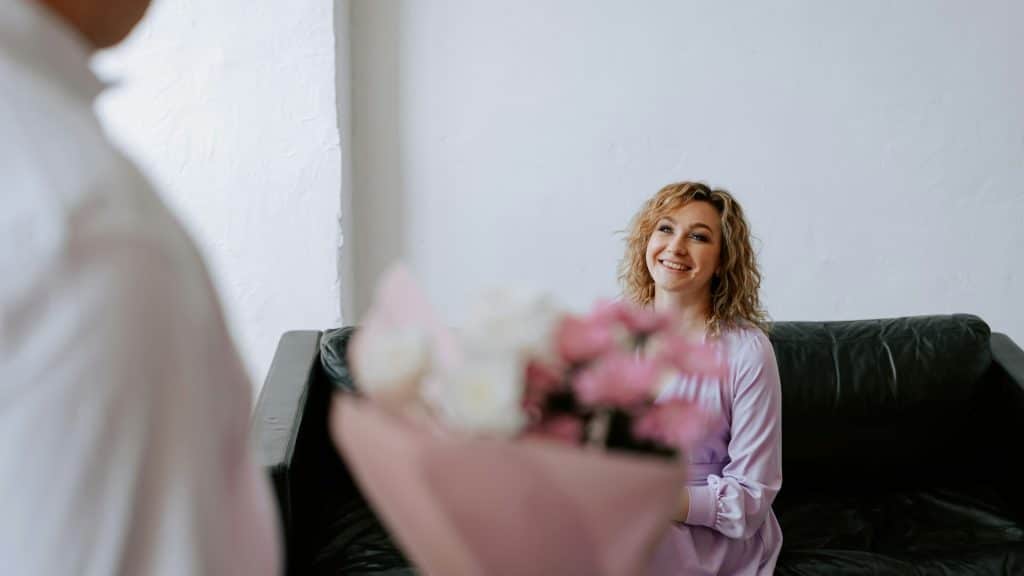 A man surprising his wife with a bouquet of flowers.
