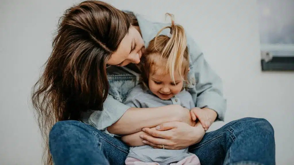 A parent sitting and cuddling a young child.