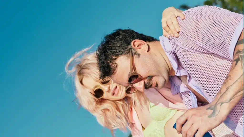 A man and a woman on a beach with trees in the background.