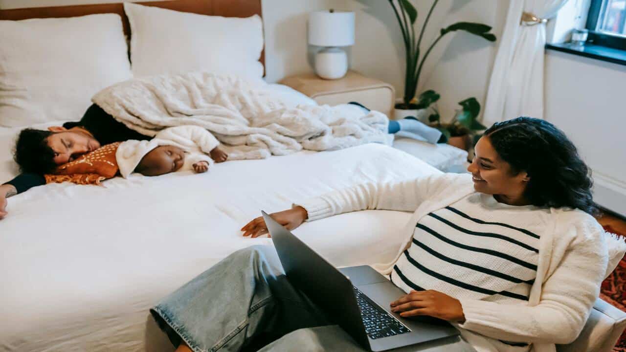 A smiling woman watching her husband and baby
