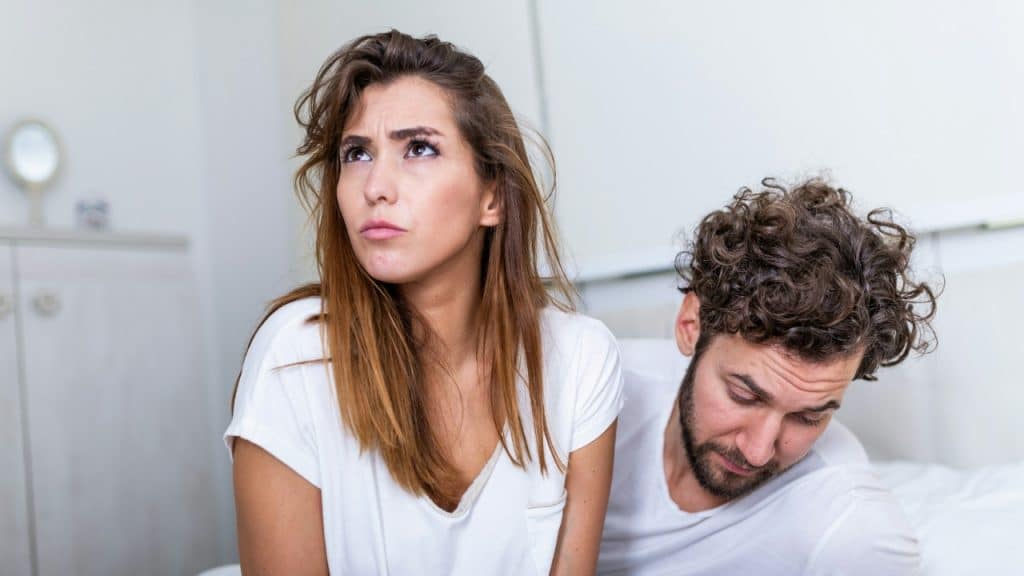 A woman looks upward with a frown while a man looks down beside her.