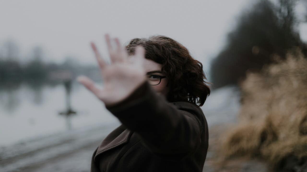 A woman holding up her hand as if to say “bye”