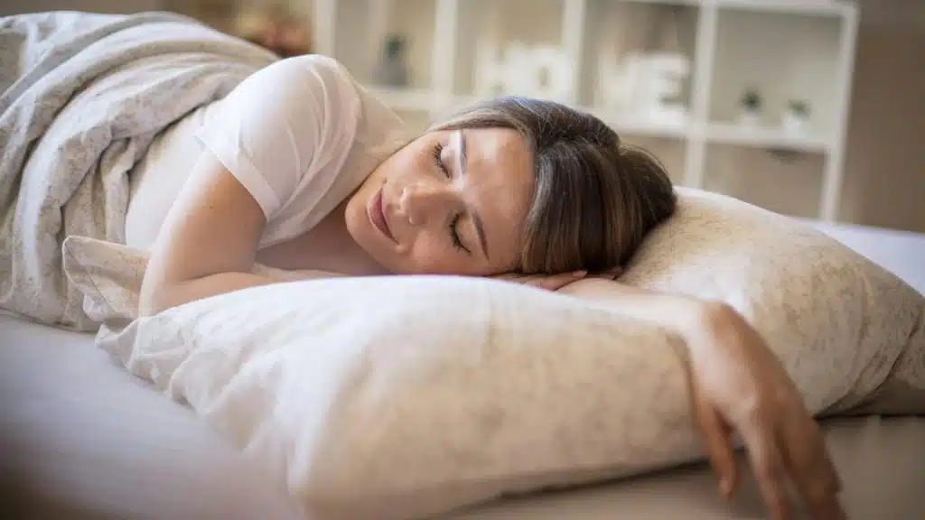 A woman sleeping soundly in bed with a smile on her face.