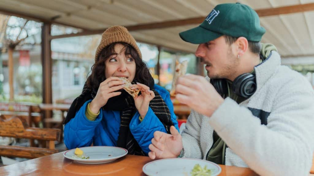 A man and woman sitting at a table eating food.