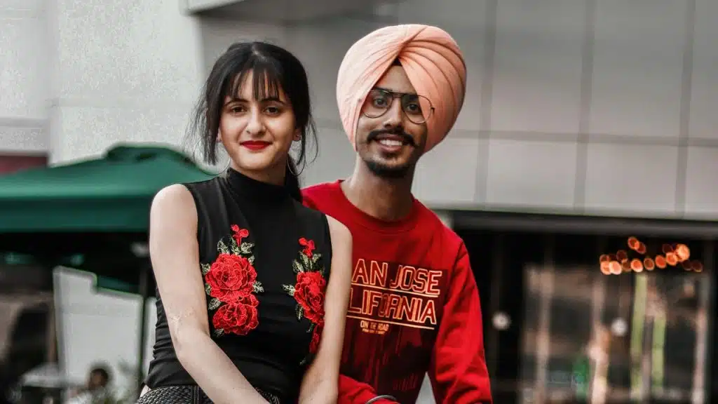 A smiling man and woman sitting on a bench near the outdoors during the daytime.