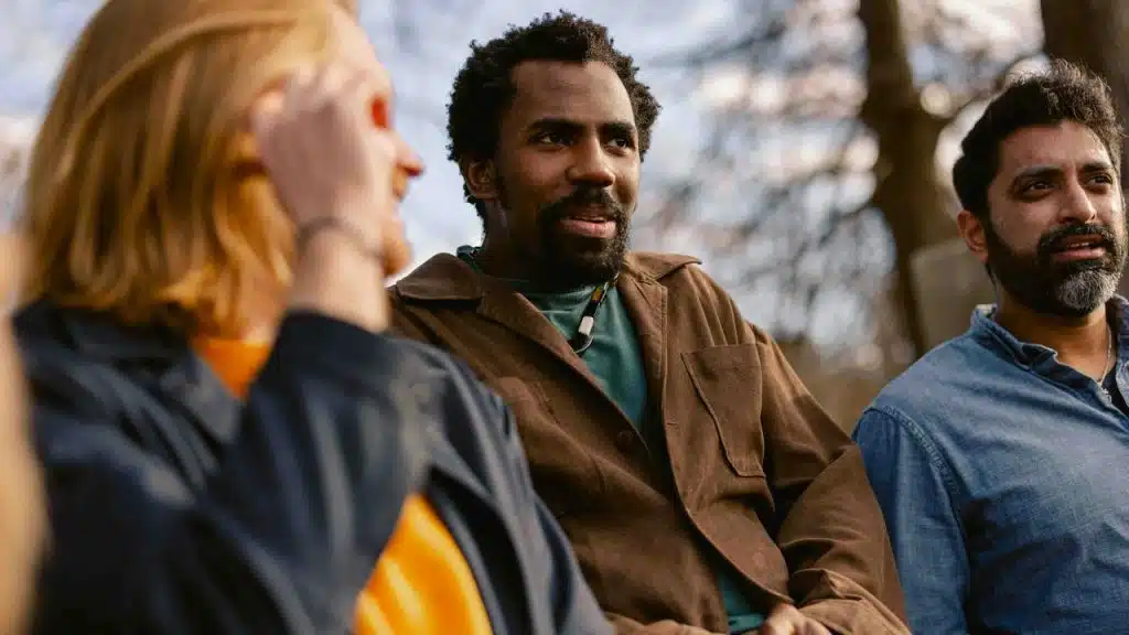A group of three people talking together outdoors.