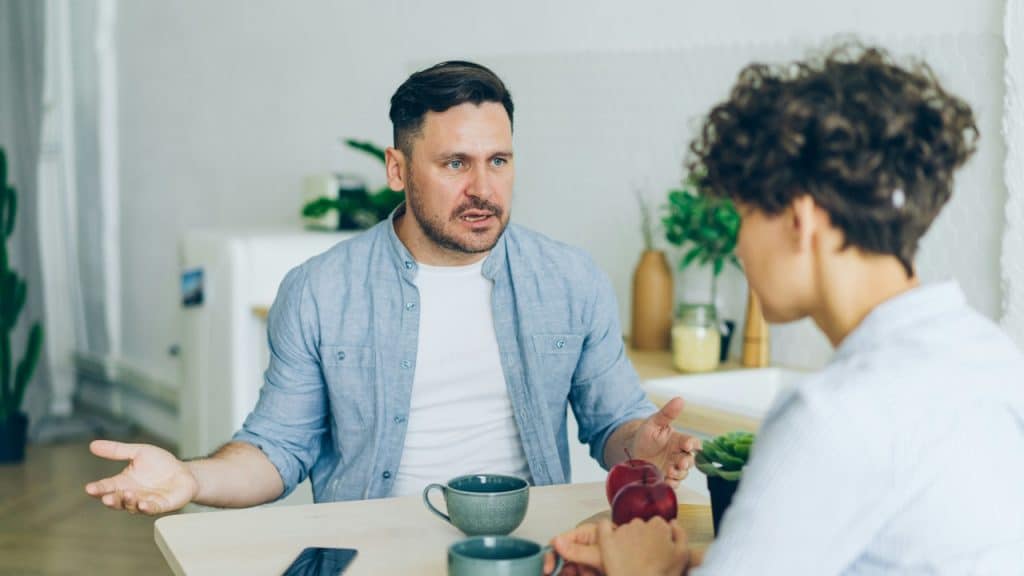 A man sitting at a table arguing with his man.
