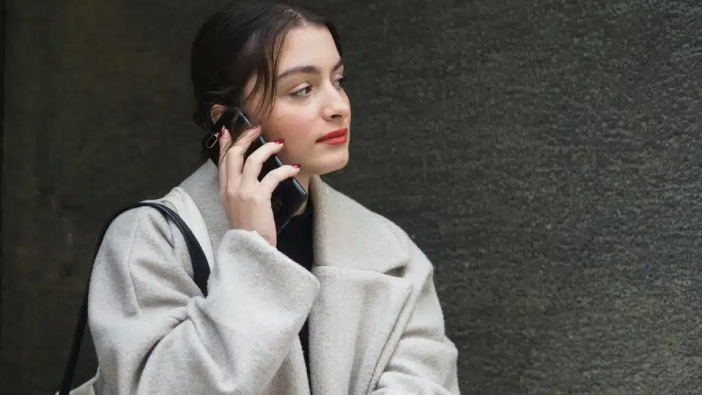 A woman talking on a smartphone while standing outdoors.
