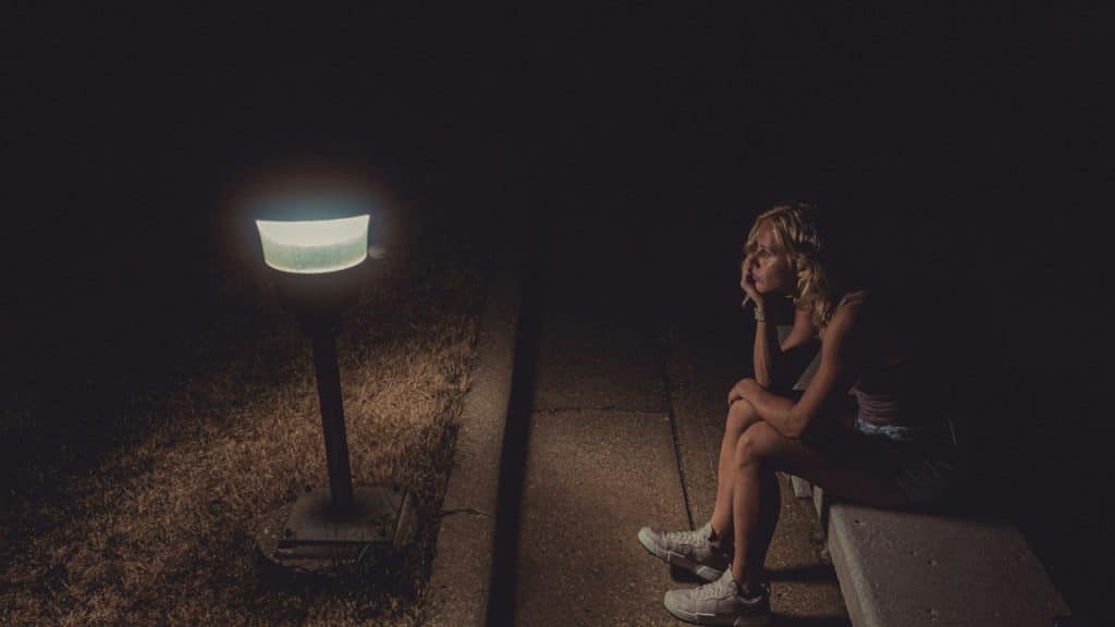 A woman in black tank top sitting on the concrete floor.