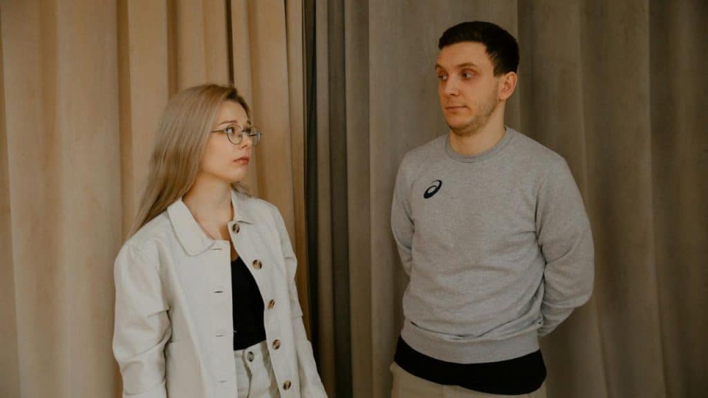 A woman in a pink sweater sits alone in a red diner booth with coffee.