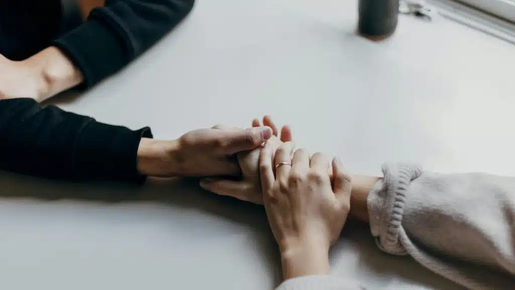 A close-up of two people holding hands across a table.