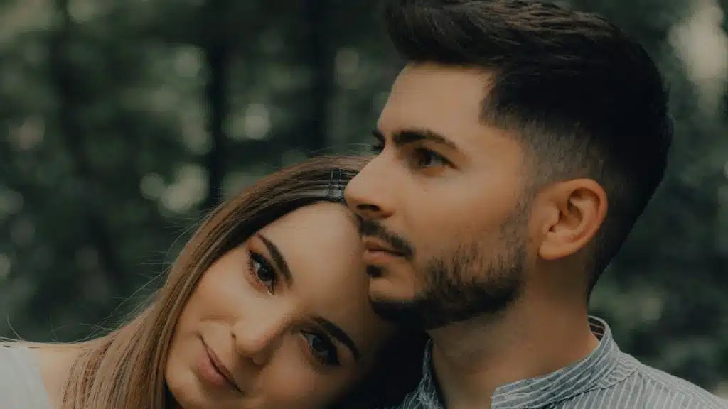 A woman resting her head on a bearded man’s shoulder.