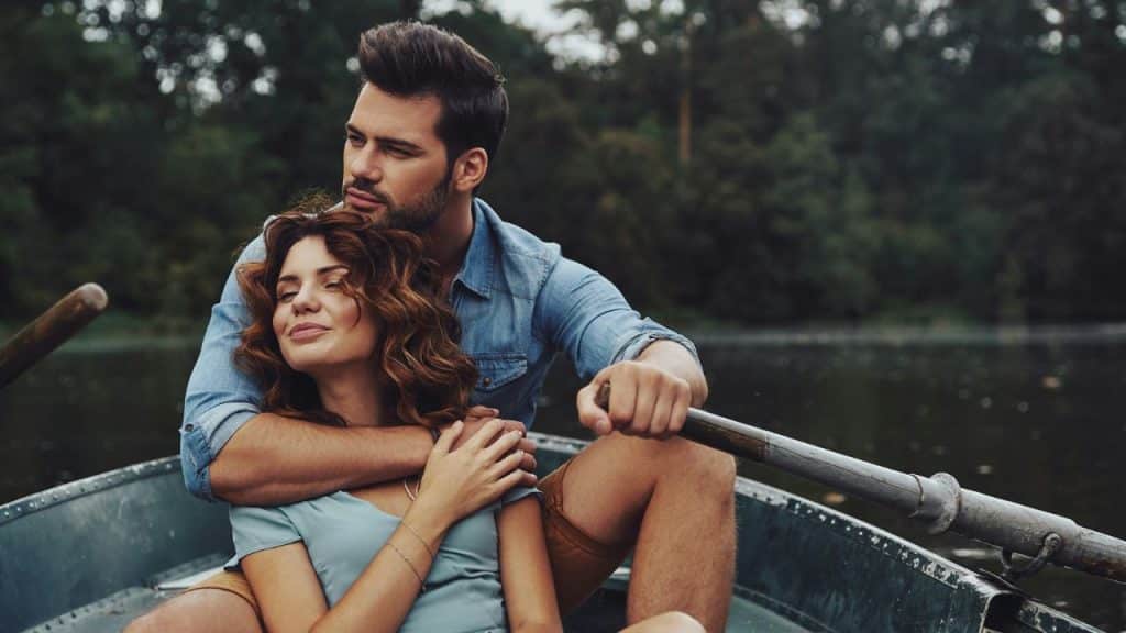 A man and woman sit together in a small boat on a body of water.