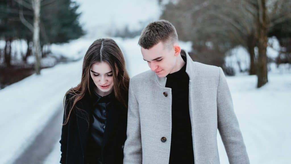 A couple talking while walking on the snow.