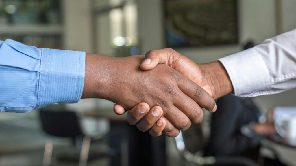 A photo of two people shaking hands inside an office.