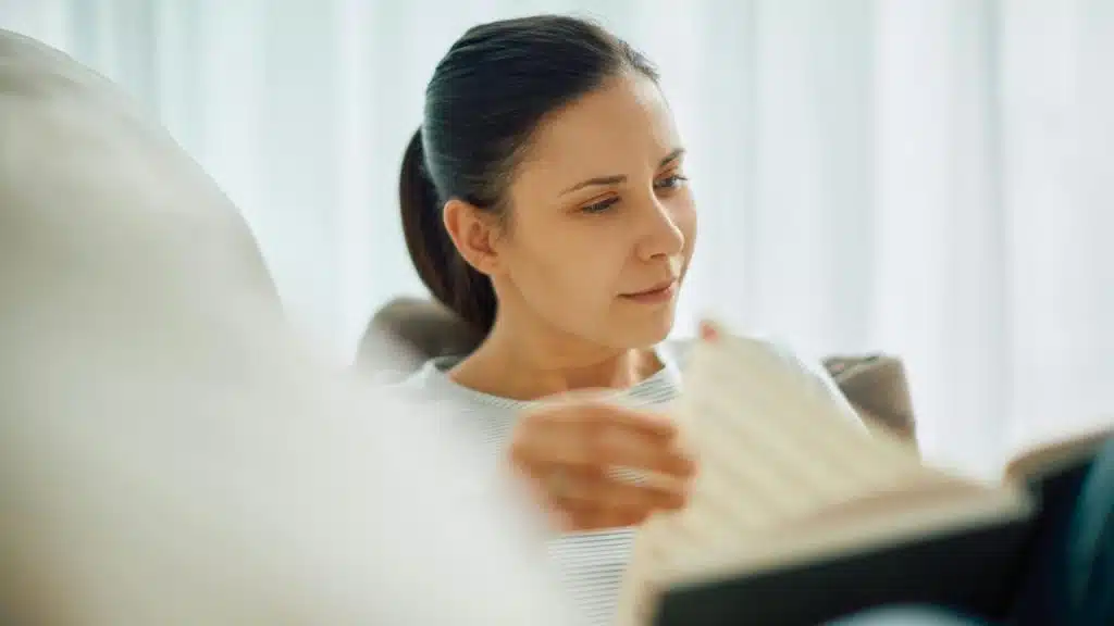 A woman reading a book while sitting comfortably indoors.