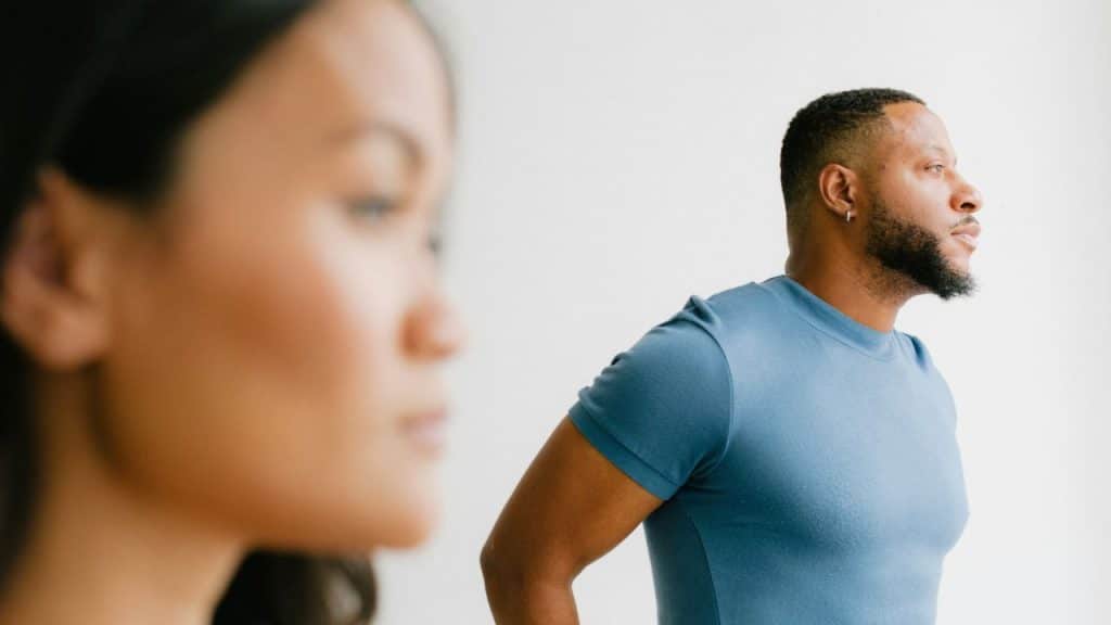 A man in a blue shirt looks to the side, with a blurred woman in the foreground.