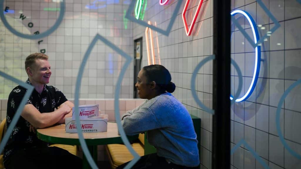 A couple conversing while sitting at a table in a cafe.