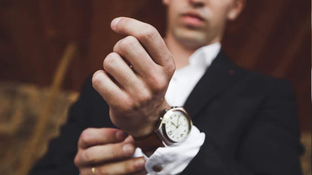 A man in a black suit wearing a new luxury-style watch.