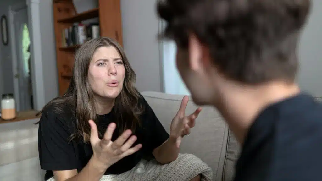 A woman is sitting on a couch talking to a man.