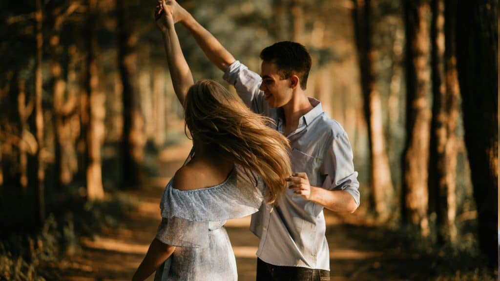 A couple dancing on a path in the forest.