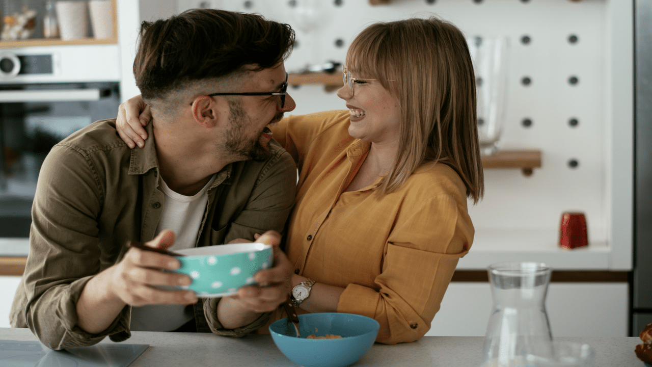 A couple laughing together in the kitchen