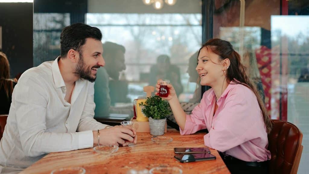 A couple having coffee is sitting at a table.