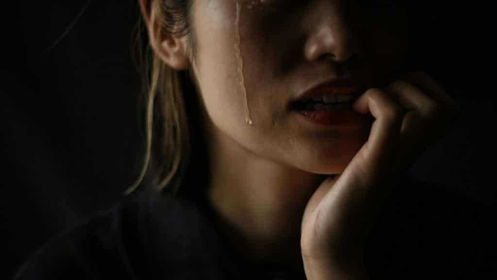 A close-up of a person's face with a single tear running down their cheek.
