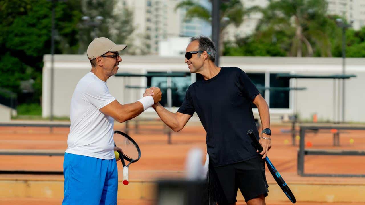 A handshake between two men on a tennis court.