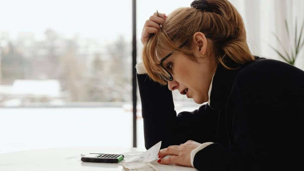 A woman reviewing bills with a calculator at a table.