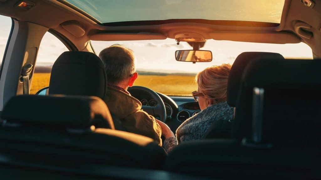 An older couple driving together at sunset.