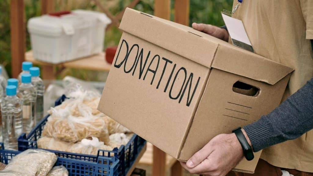 A person holding a donation box near supplies.