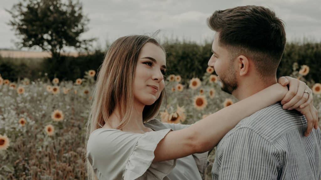 A man and a woman standing in a sunflower garden.