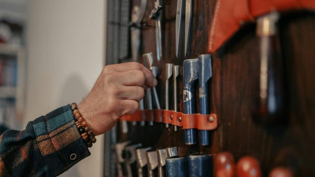 A person selecting a tool from a wall rack.