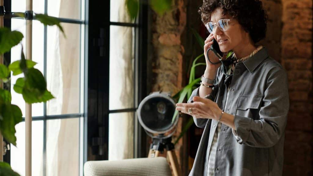 A woman talking on the phone near a window.