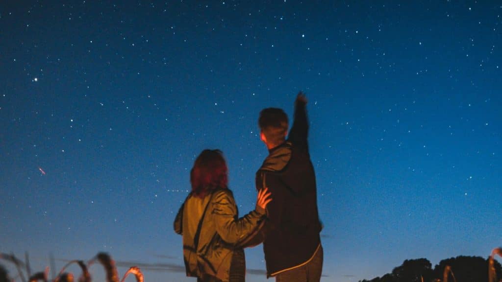 A couple stargazing together under a clear night sky.