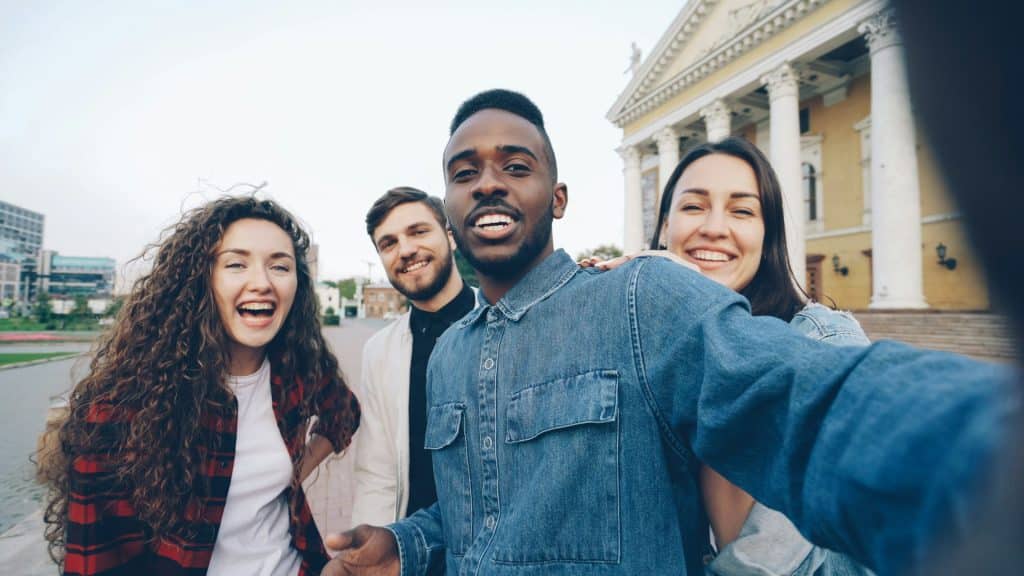A group of friends posing for a selfie and smiling.