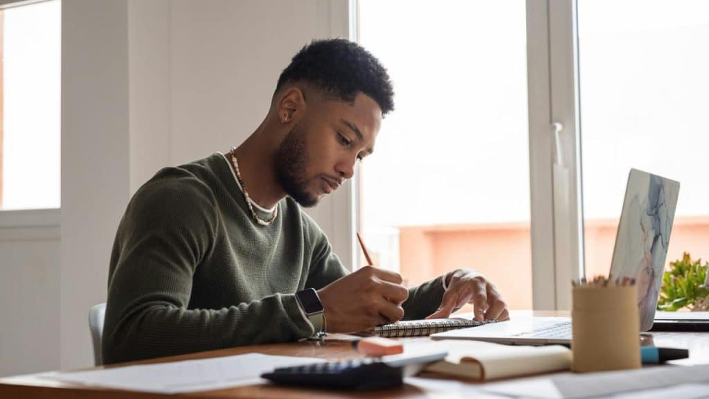 A man writing in a notebook at a desk.