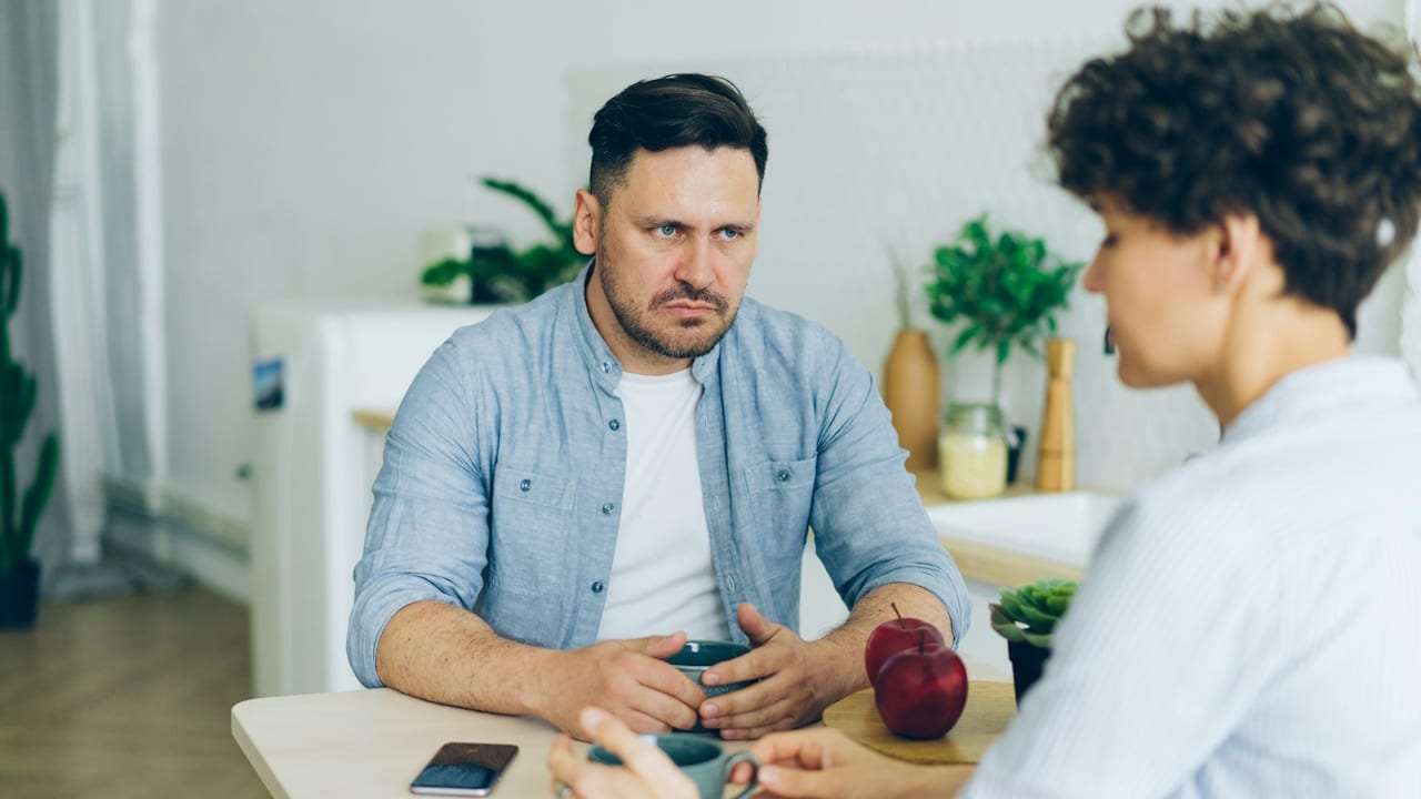 A man criticizing his wife while they are sitting at a table together.