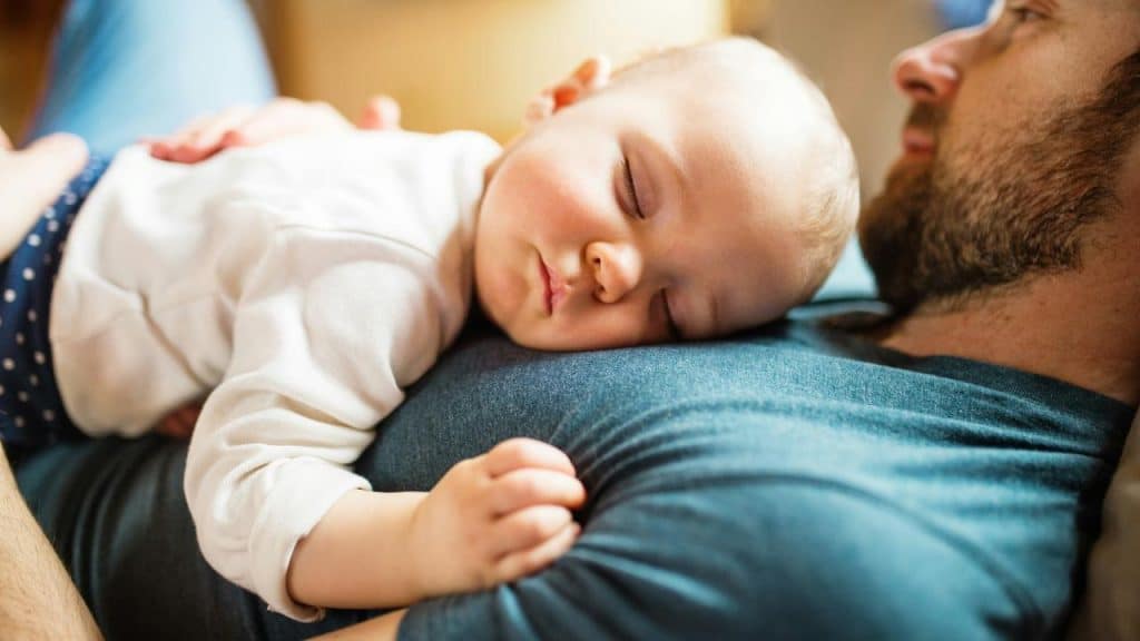 A sleeping baby resting peacefully on an adult’s chest.