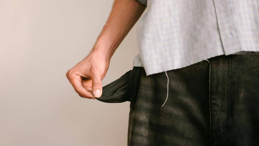 An empty pants pocket being pulled out by a person’s hand.