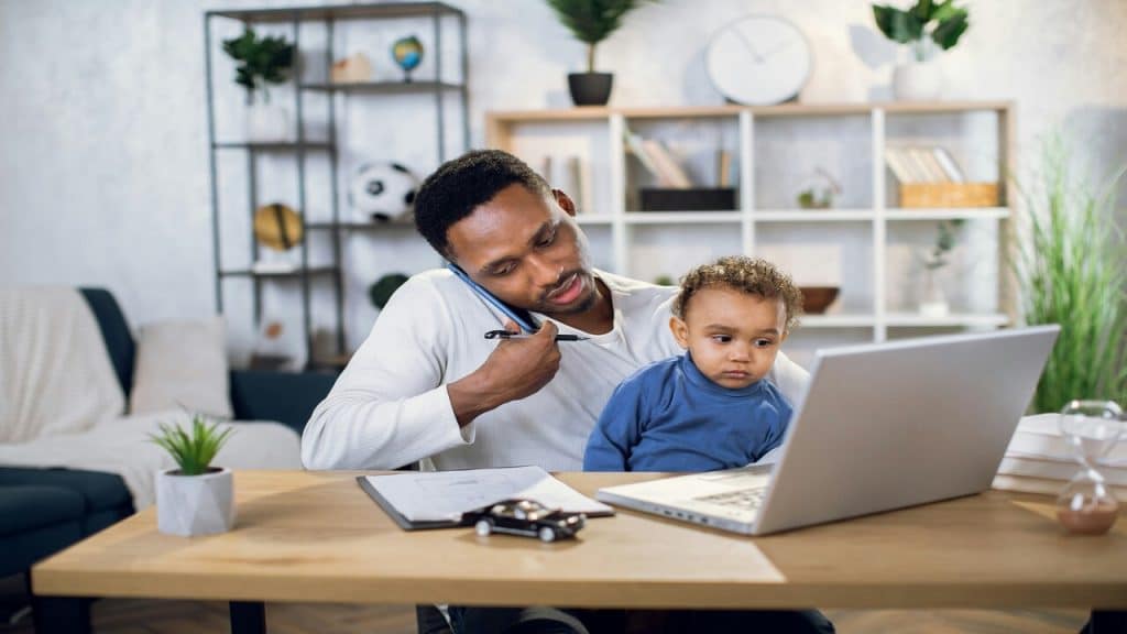 A dad working while taking care of his son