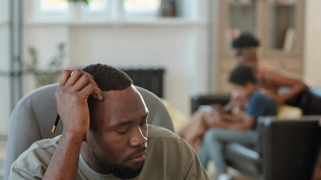 A man looking stressed while sitting with his head resting on his hand.