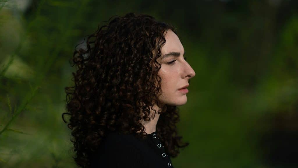 A curly-haired woman looking lost in thought.