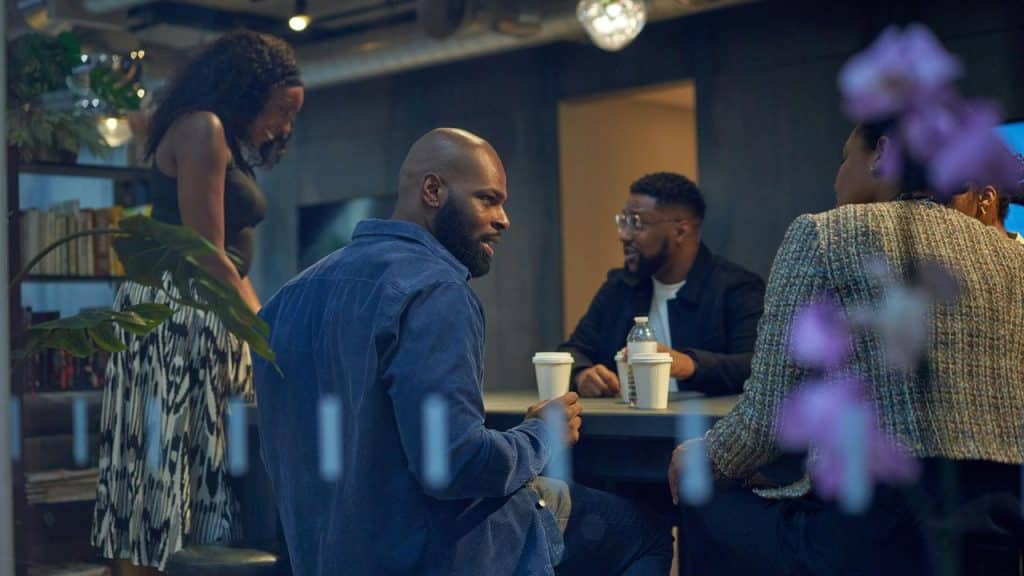 A group of people talking around a table in a modern indoor café or office space.