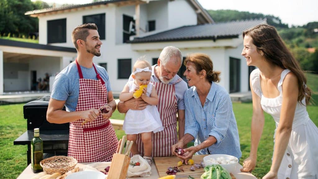 A multi-generational family cooking together outdoors.